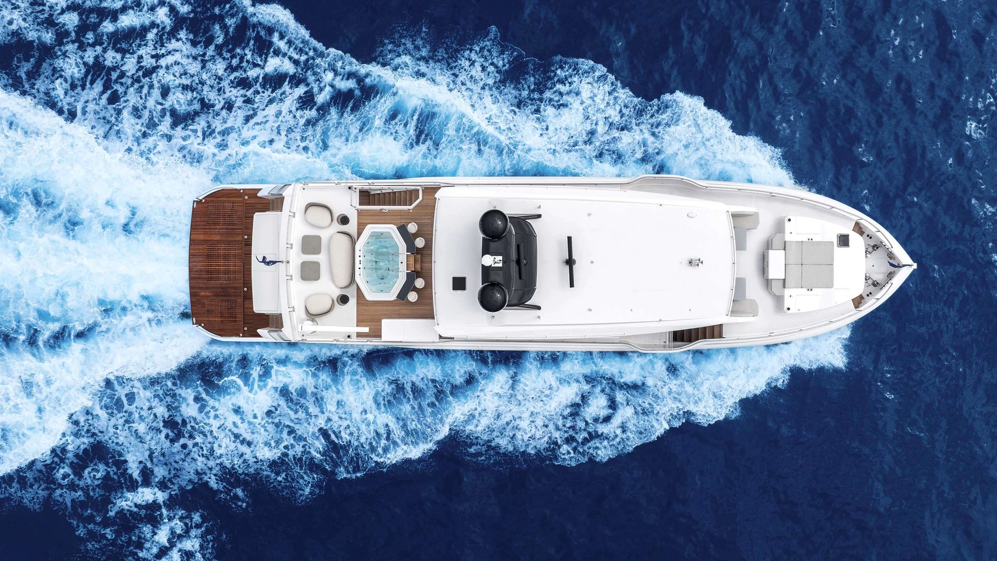 Aerial view of a luxury motor yacht cruising across deep blue open ocean